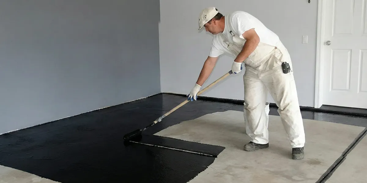 basement waterproofing professional applying waterproof coating to protect a basement floor in Louisville, KY