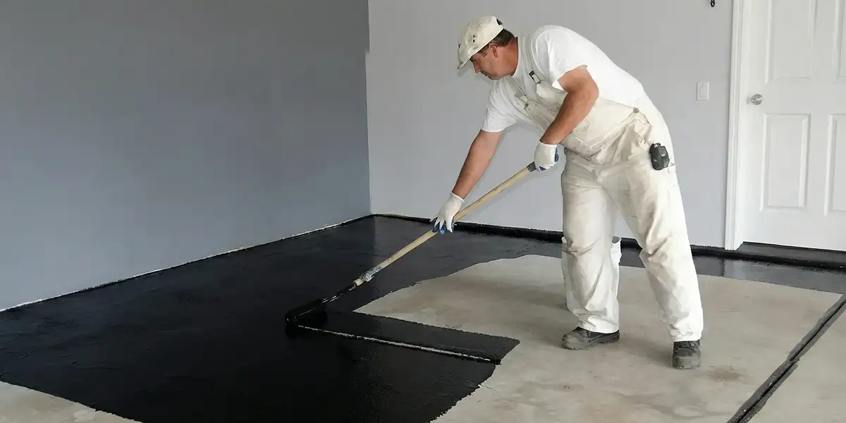 basement waterproofing professional applying waterproof coating to protect a basement floor in Louisville, KY